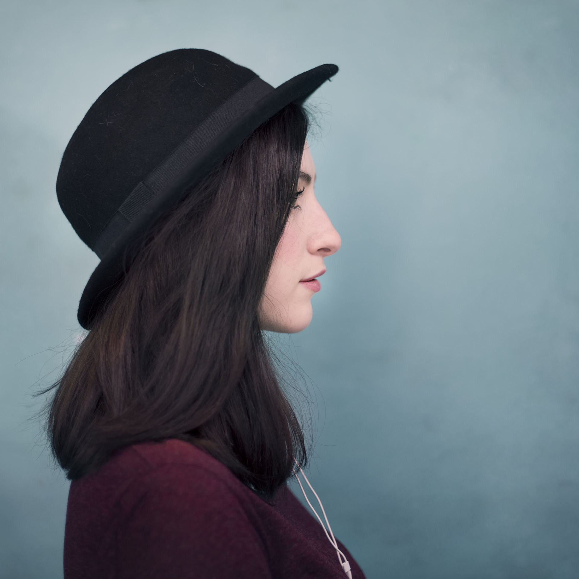 profile, brunette lady in purple shirt and black hat